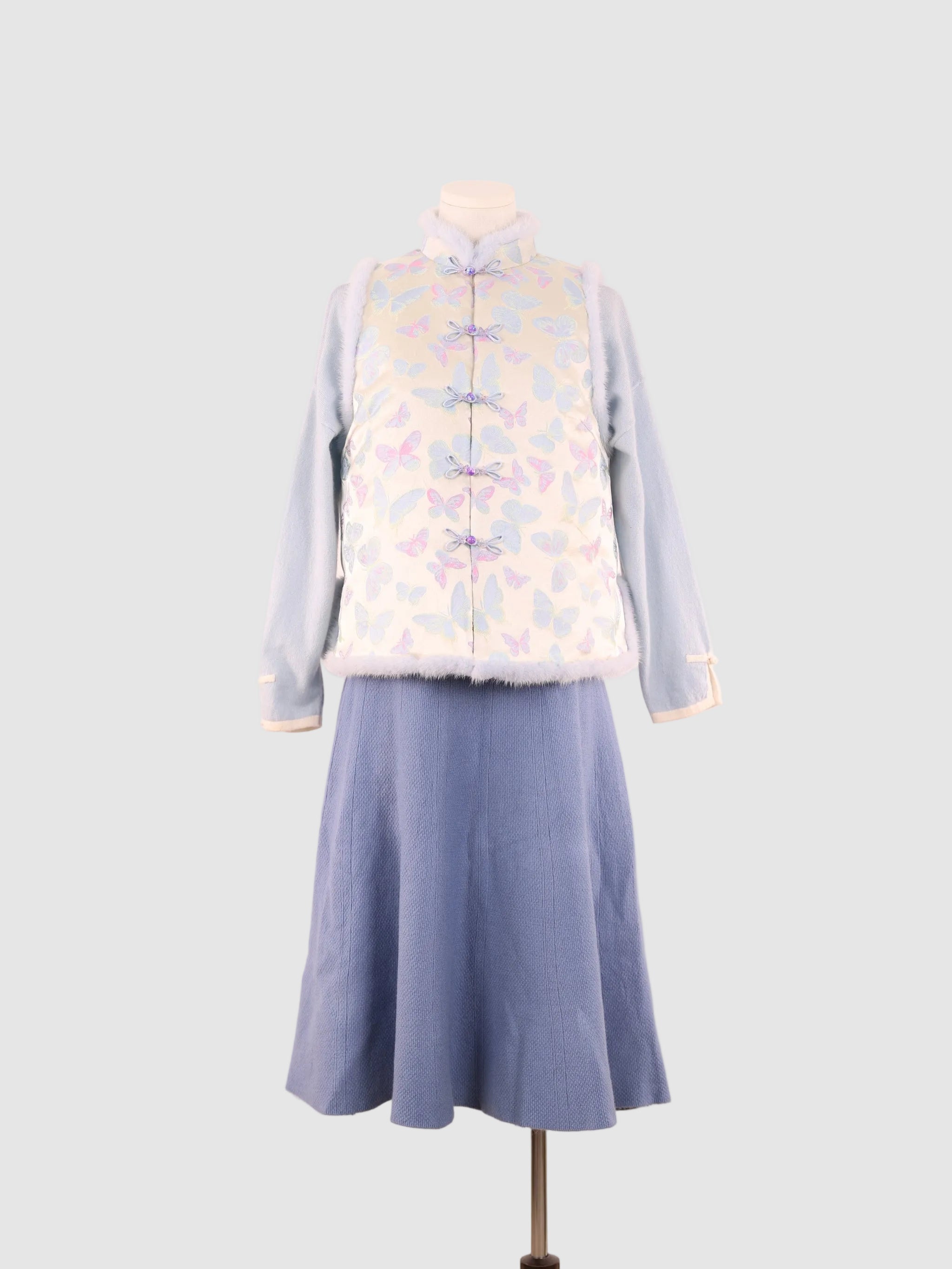 A full front view of a blue butterfly-patterned vest paired with a blue skirt.