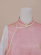 Close-up of a pink silk qipao with jacquard details, featuring a mandarin collar, pearl frog buttons, and fine piping for an elegant oriental touch.