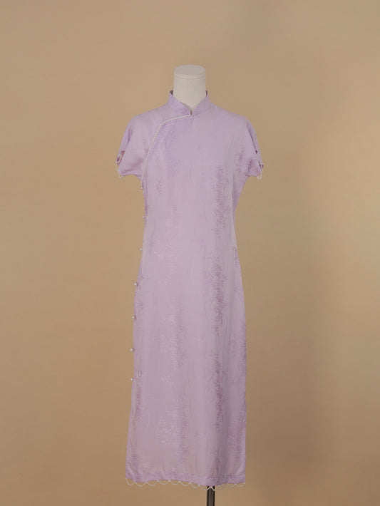Full front view of a lavender silk qipao with pearl trim, side button details, and floral jacquard texture.