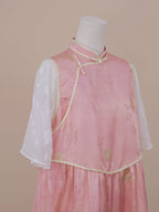 Side angle showing the diagonal frog button fastening and gold-trimmed edges of a pink silk qipao with sheer white sleeves for a soft, graceful look.