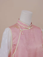Side view of a pink silk qipao with gold floral jacquard, showing the mandarin collar, diagonal frog button closure, and sheer white sleeves with delicate texture.