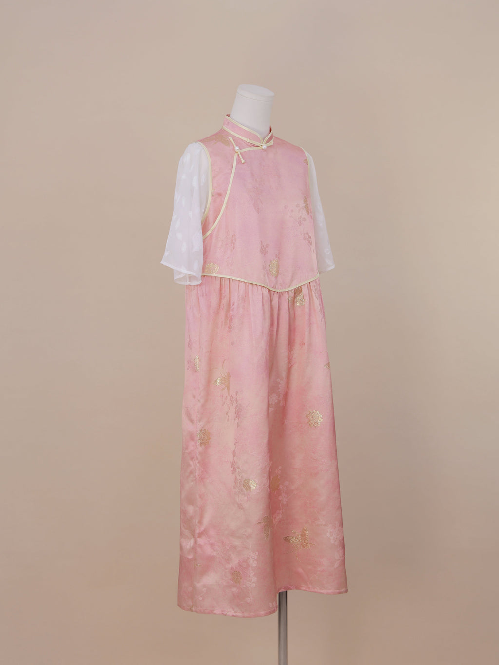 Three-quarter side view of a pink silk qipao dress with gold jacquard floral patterns, mid-calf length skirt, and a gentle A-line silhouette.