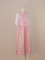 Three-quarter side view of a pink silk qipao dress with gold jacquard floral patterns, mid-calf length skirt, and a gentle A-line silhouette.