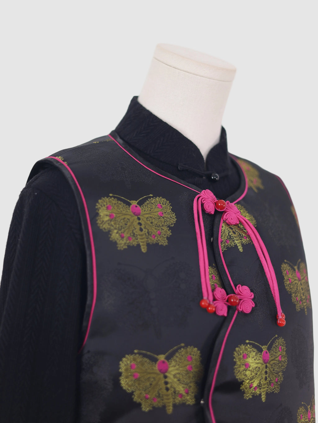 Close-up side detail of butterfly jacquard vest with pink contrast piping