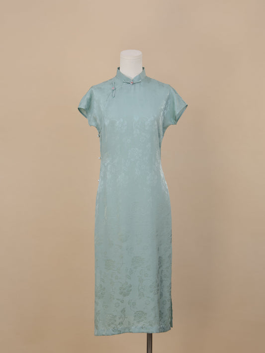 Full frontal view of a Celadon Blue silk cheongsam featuring short sleeves, Mandarin collar, floral jacquard pattern, and side pearl button accents.
