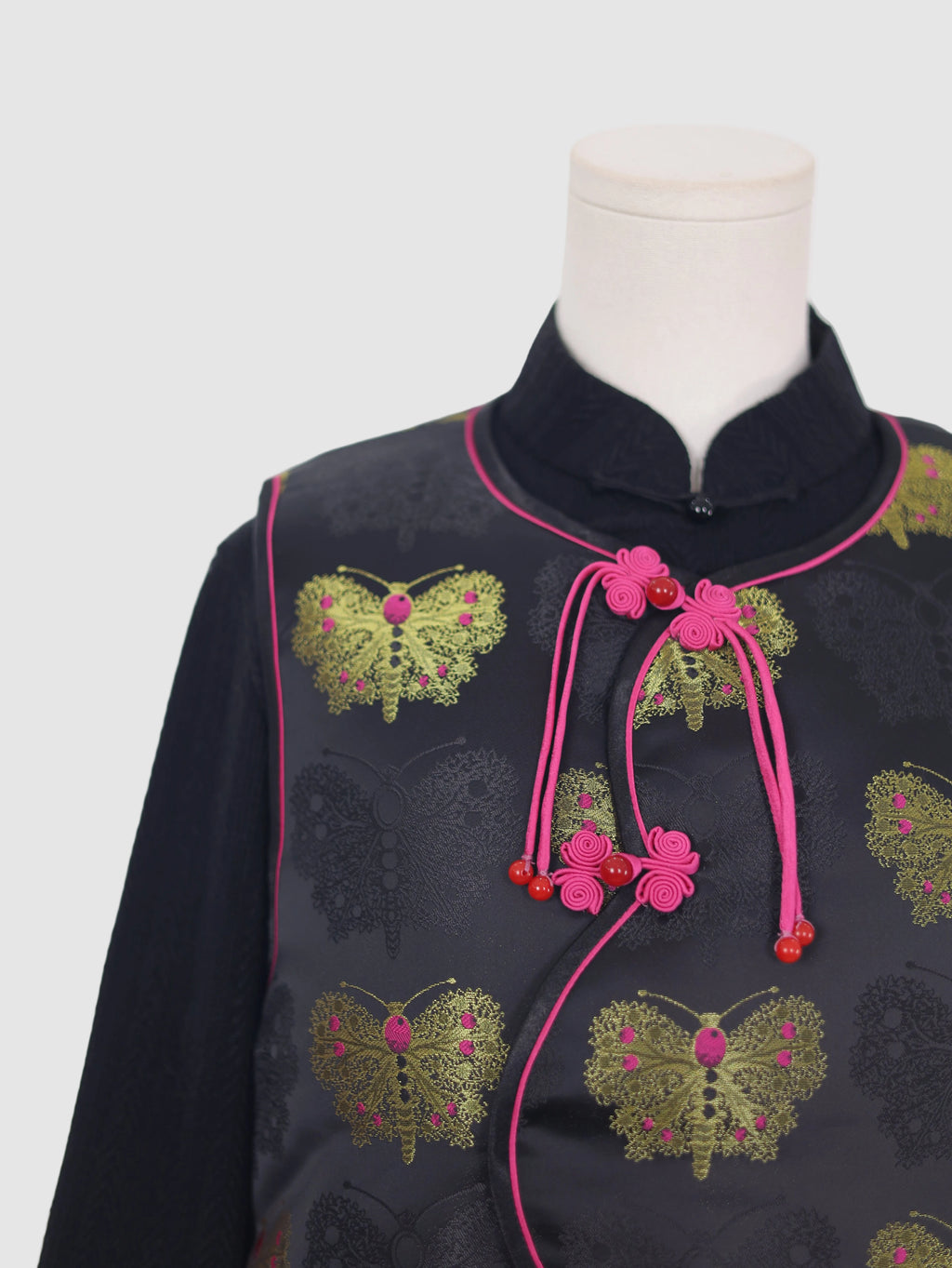 Close-up of frog button closure and pink piping on butterfly vest