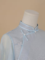 Collar detail of light blue silk cheongsam with orchid print, featuring classic stand collar and pearl button fastening.