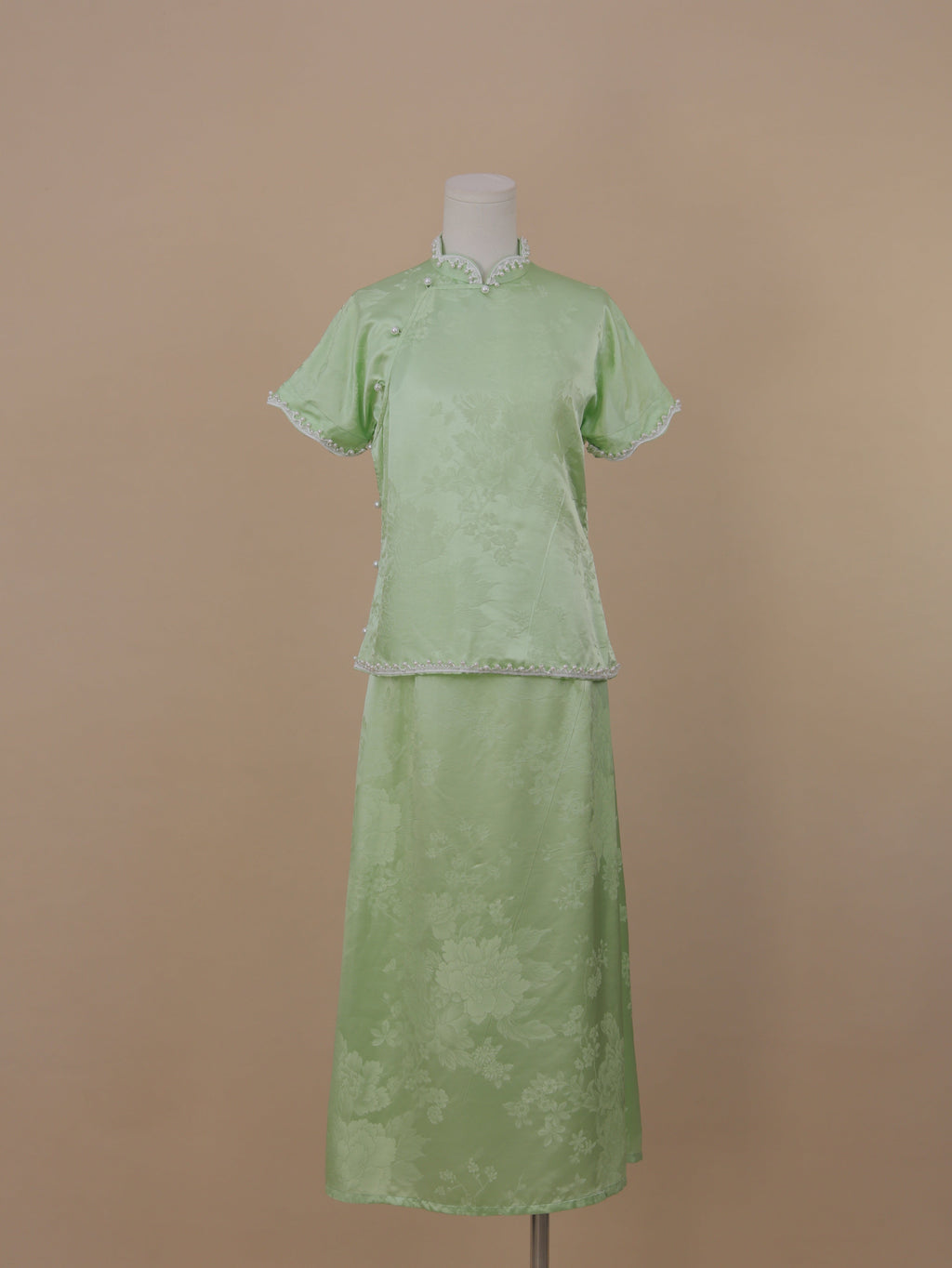 Full front view of pale green silk qipao set with jacquard floral pattern and mid-calf skirt