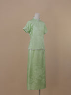 Side view of pale green silk qipao set showing traditional side fastening and elegant drape