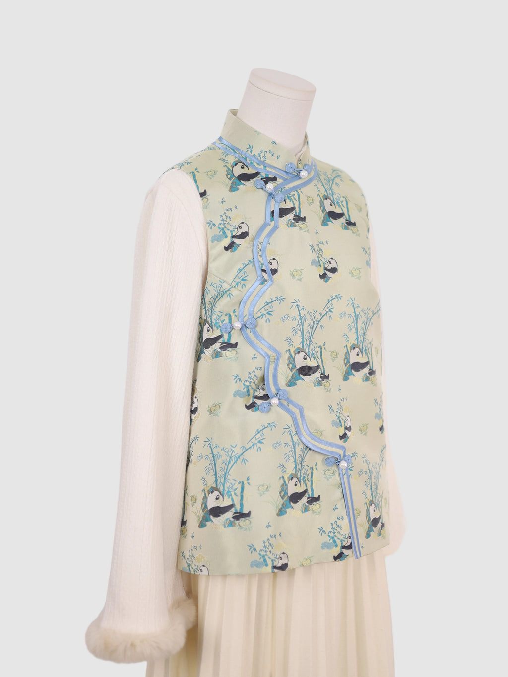 Half side view of pastel green panda print vest with contrast piping detail