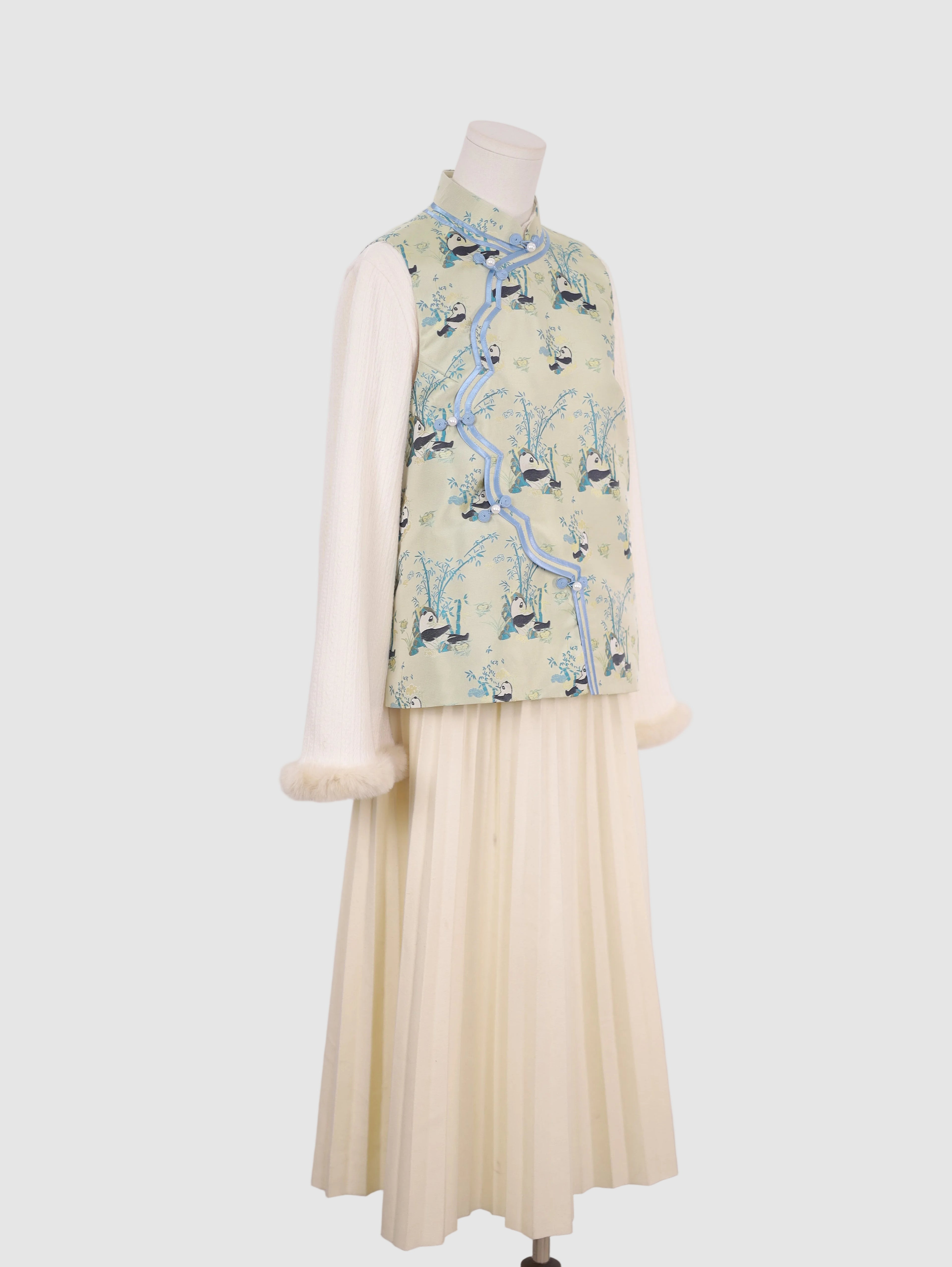 Side view of pastel green panda print vest with blue contrast piping
