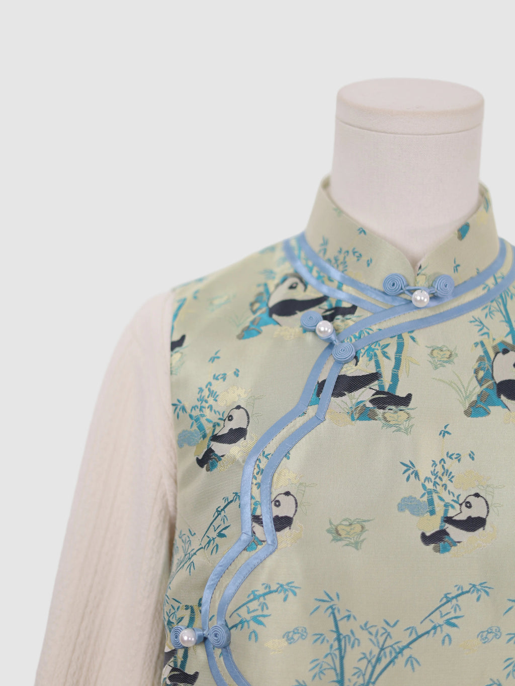 Close-up of frog button closure and curved wave-front design on panda print vest