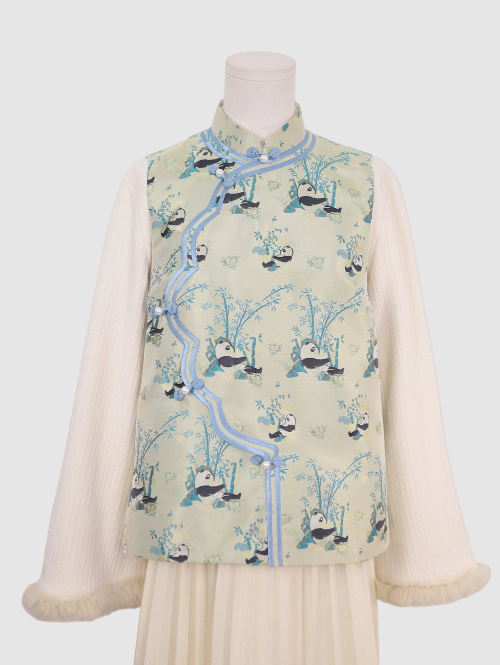 Half front view of pastel green panda wave-front vest with frog button closure