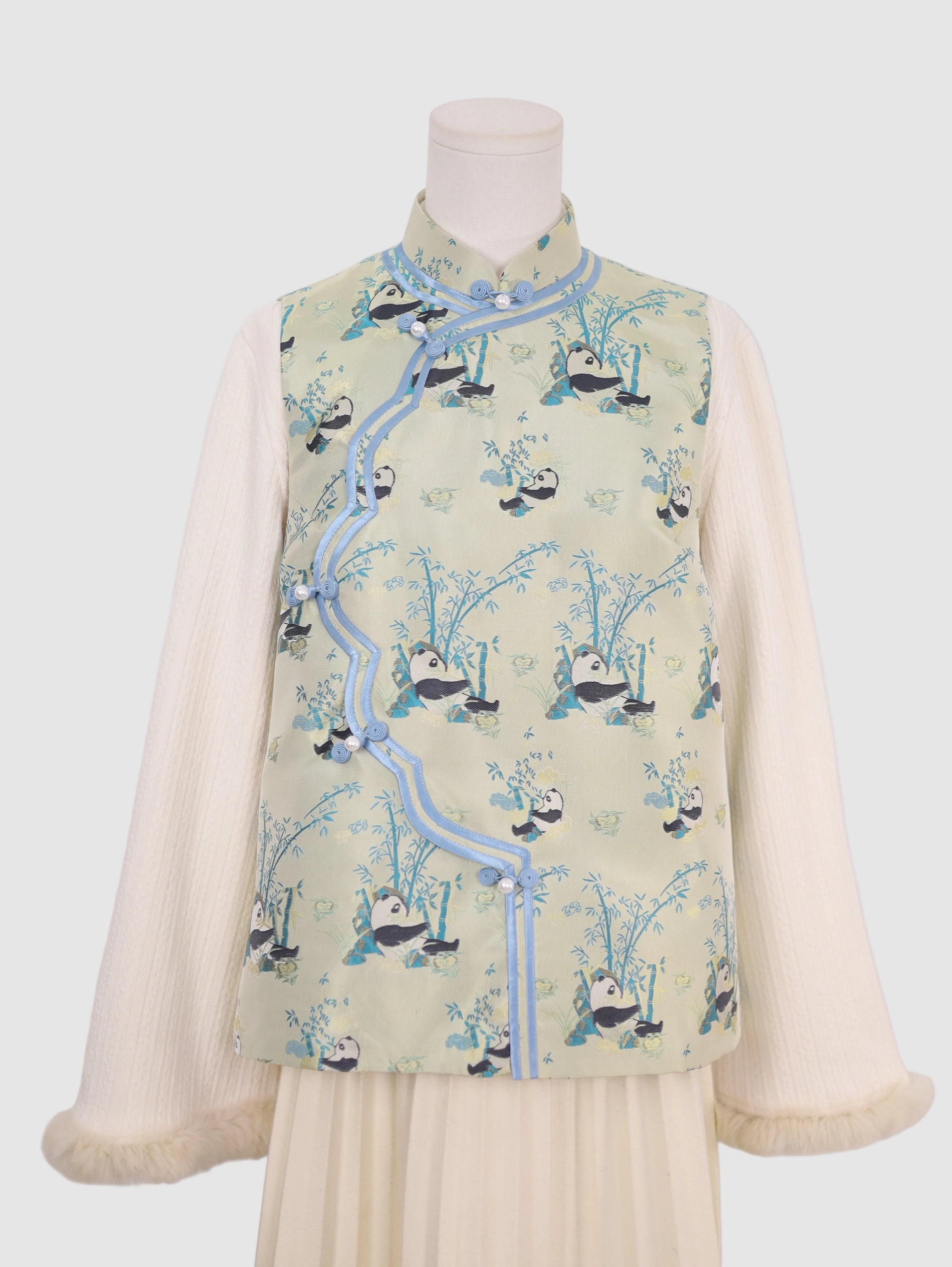 Half front view of pastel green panda wave-front vest with frog button closure