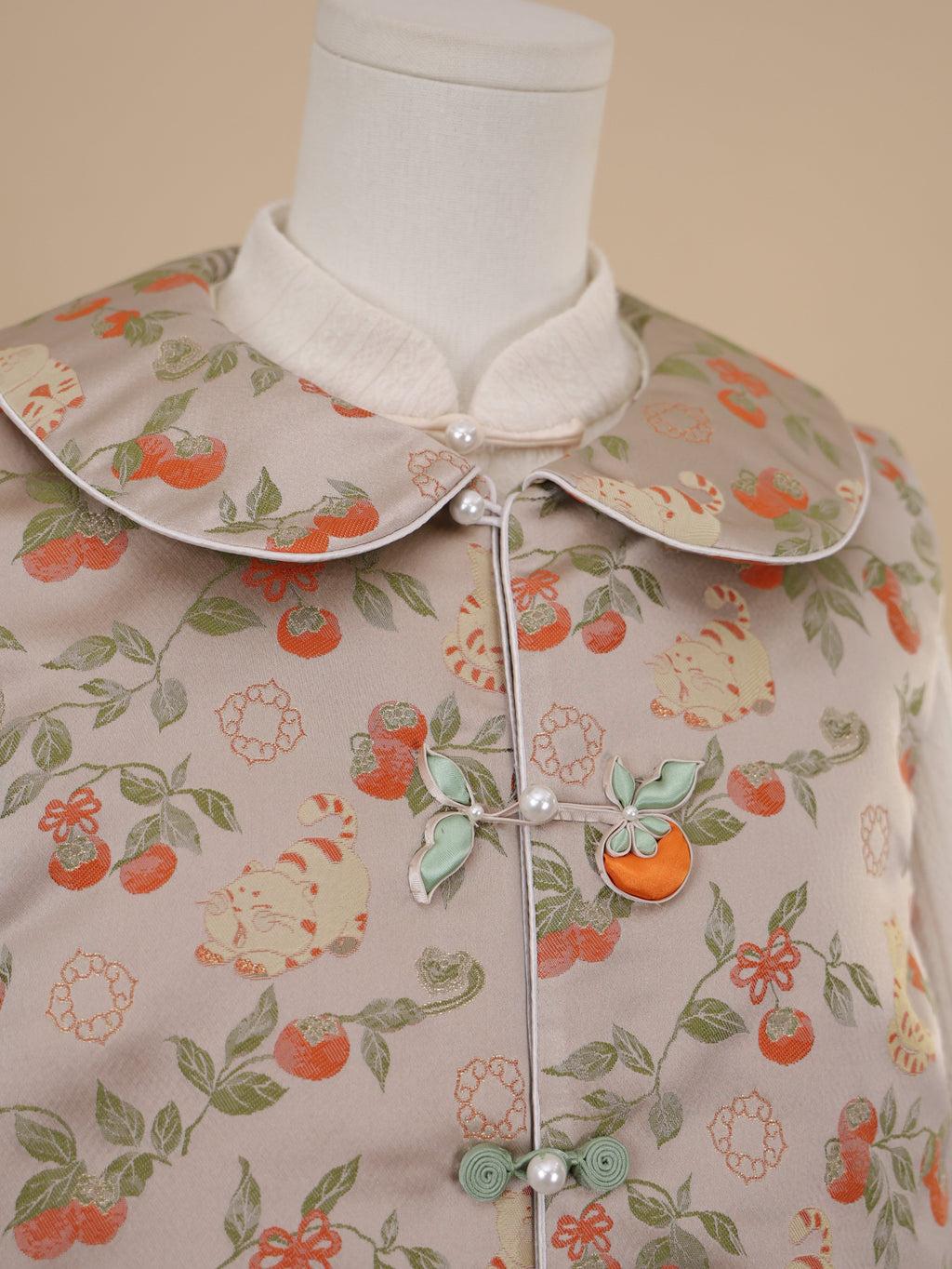 Close-up of persimmon and cat motif on beige vest