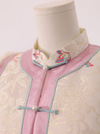 Close-up of frog button closure and collar detail on pink and white butterfly vest