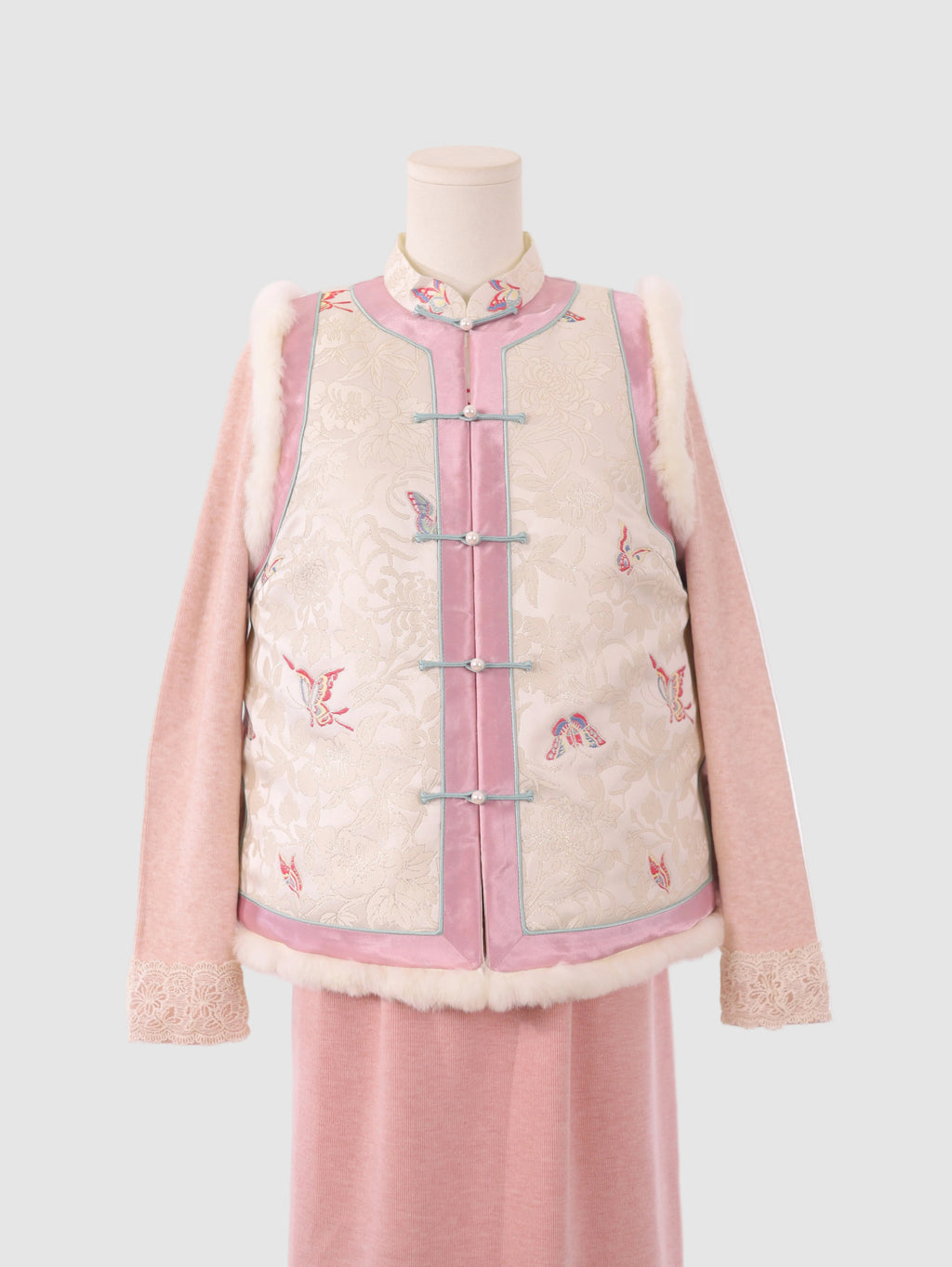 Front half view of pink and white butterfly vest with frog buttons and fur trim