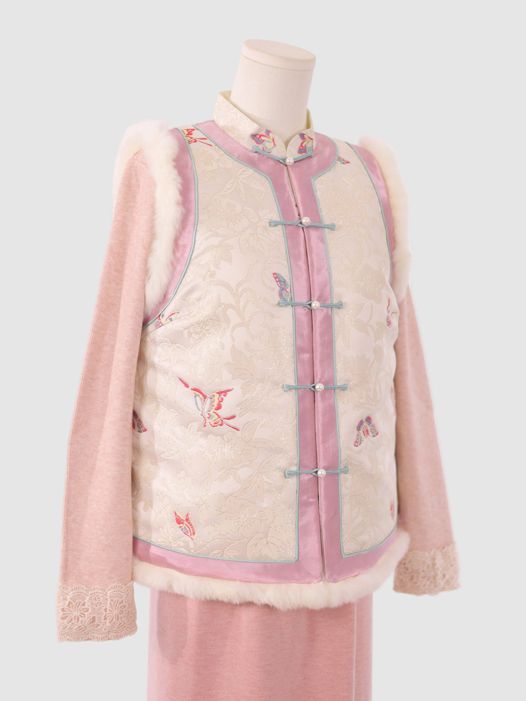 Side half view of pink and white butterfly jacquard vest showing silhouette and fur edging