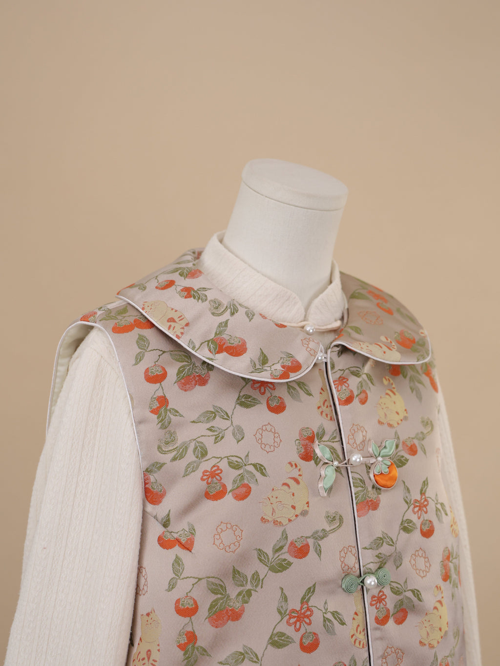 Close-up of rounded collar and frog button detail on persimmon print vest