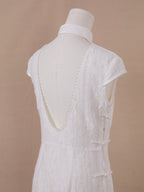 Backless detail of white lace qipao cheongsam with deep V open back and pearl embellishment.